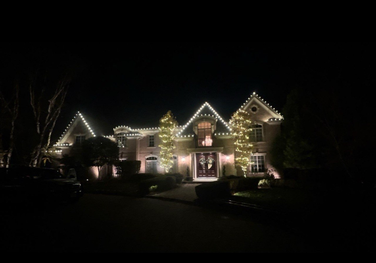 Brick home with roofline and lit tree wraps