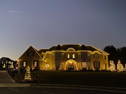 Large home outlined in warm white lights with lit evergreens