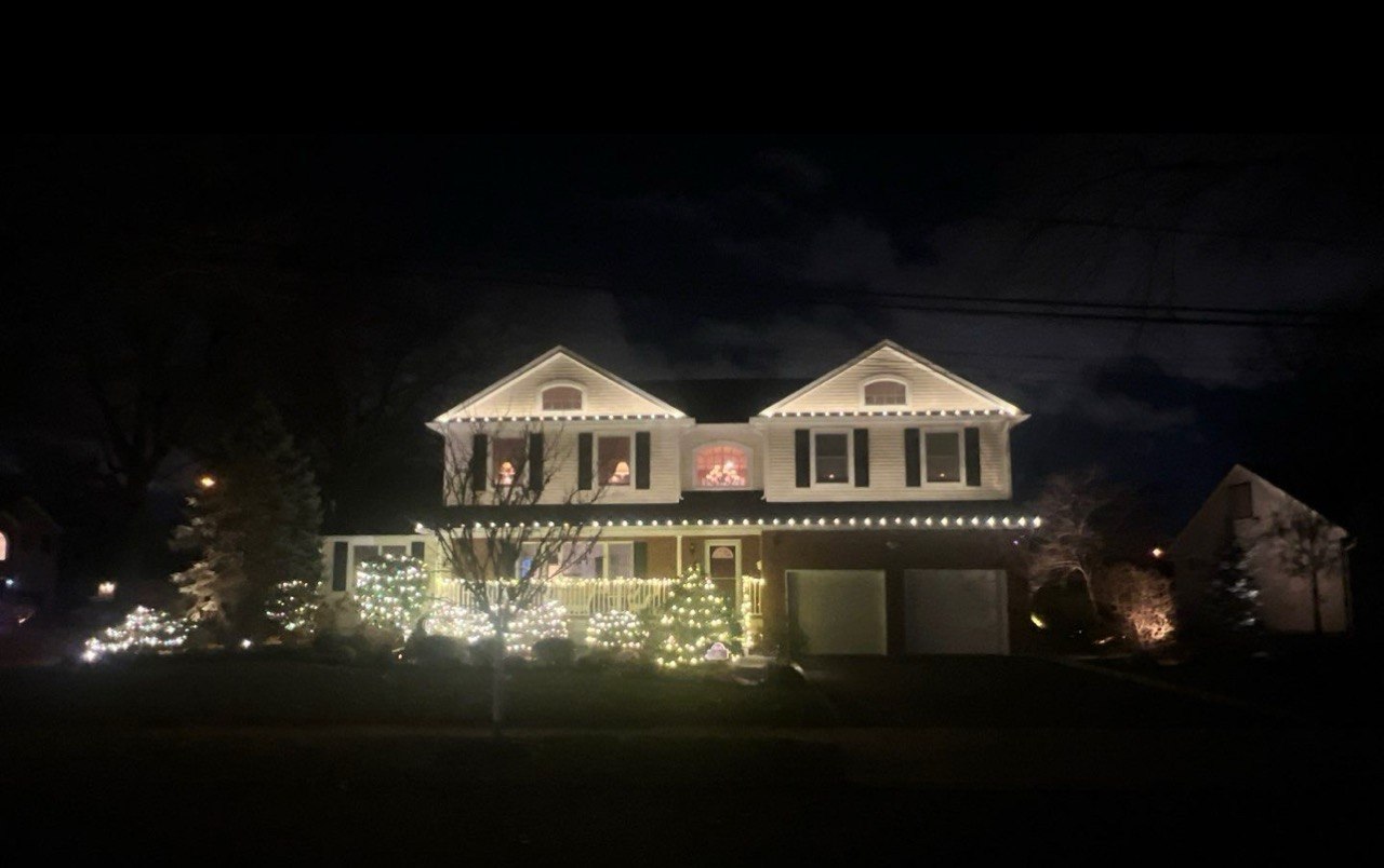 Twin-gable home with lit shrubs