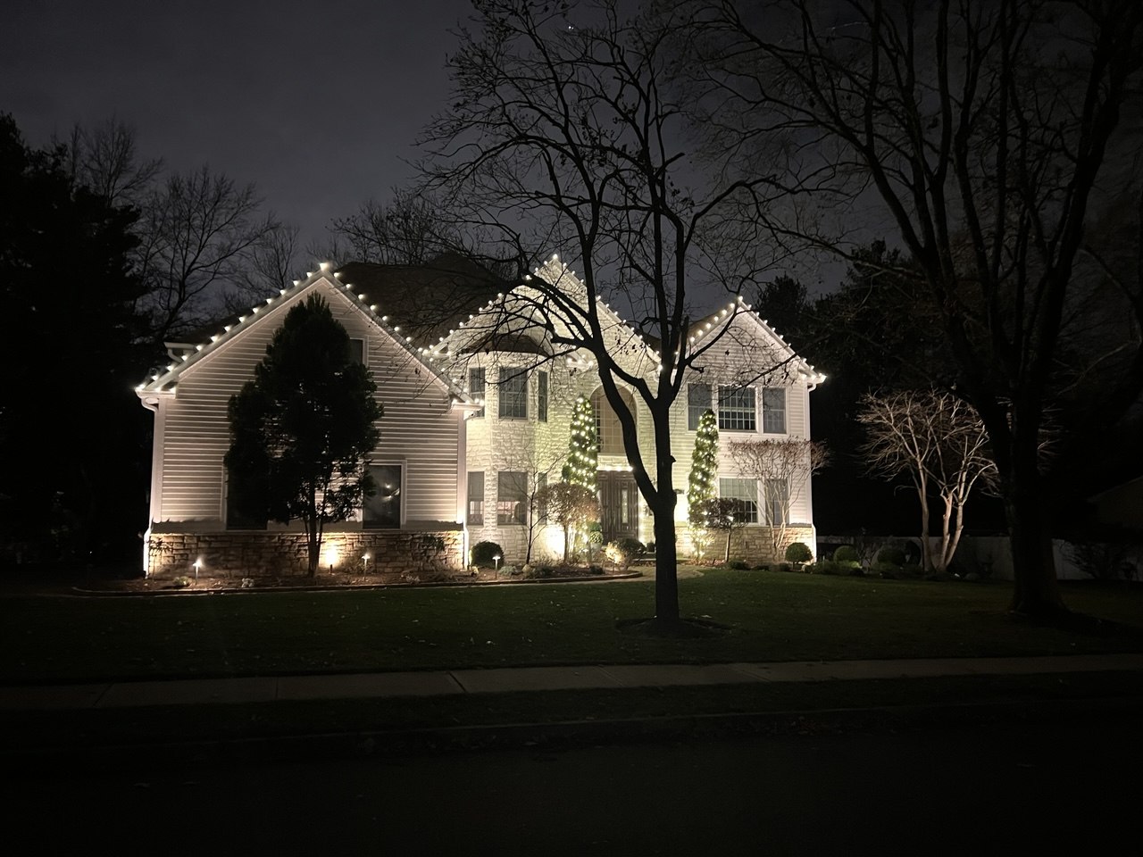 Home with roofline lights and wrapped evergreens